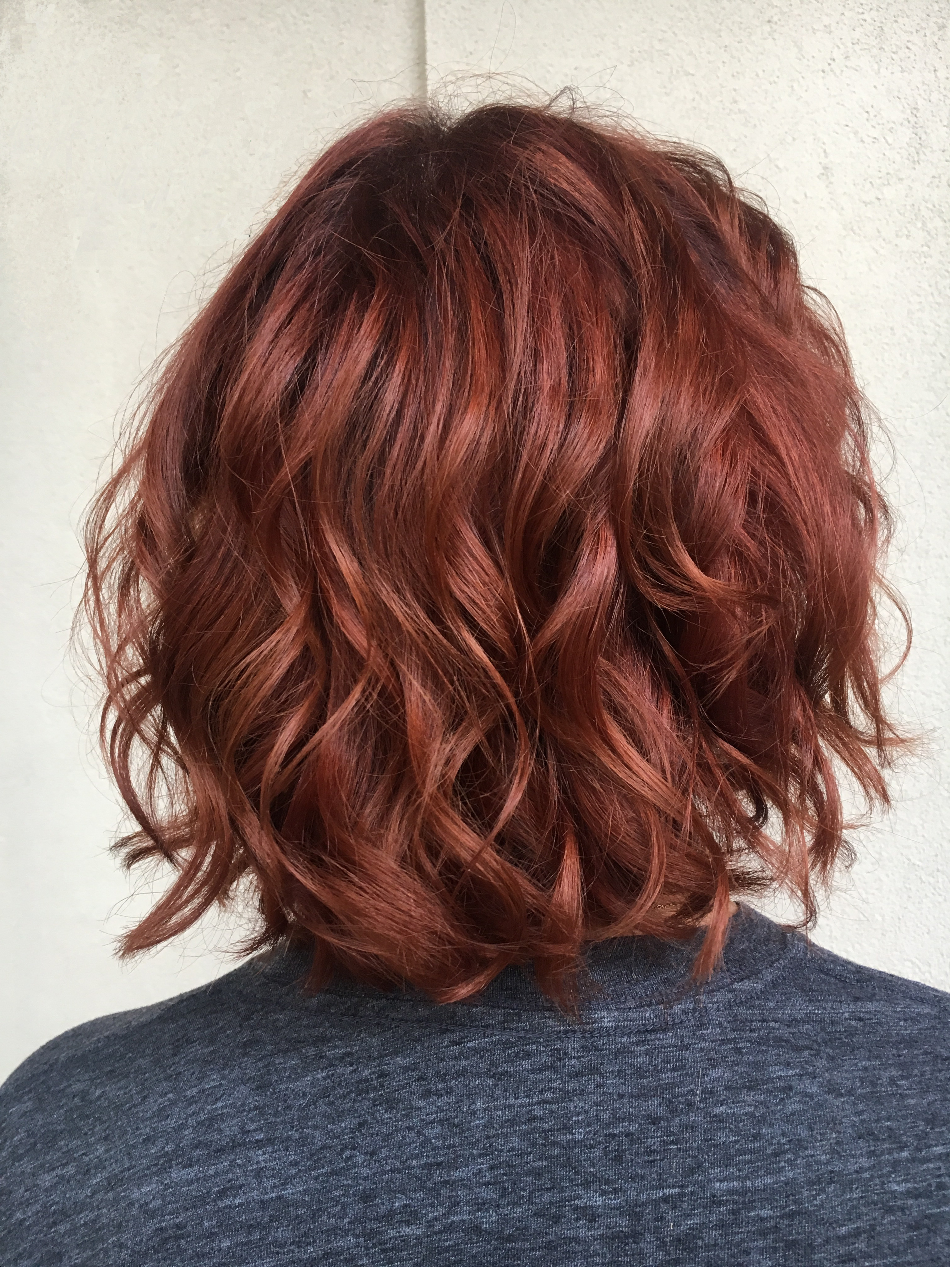 Photo of woman with wavy, short hair with a deep copper hair color.