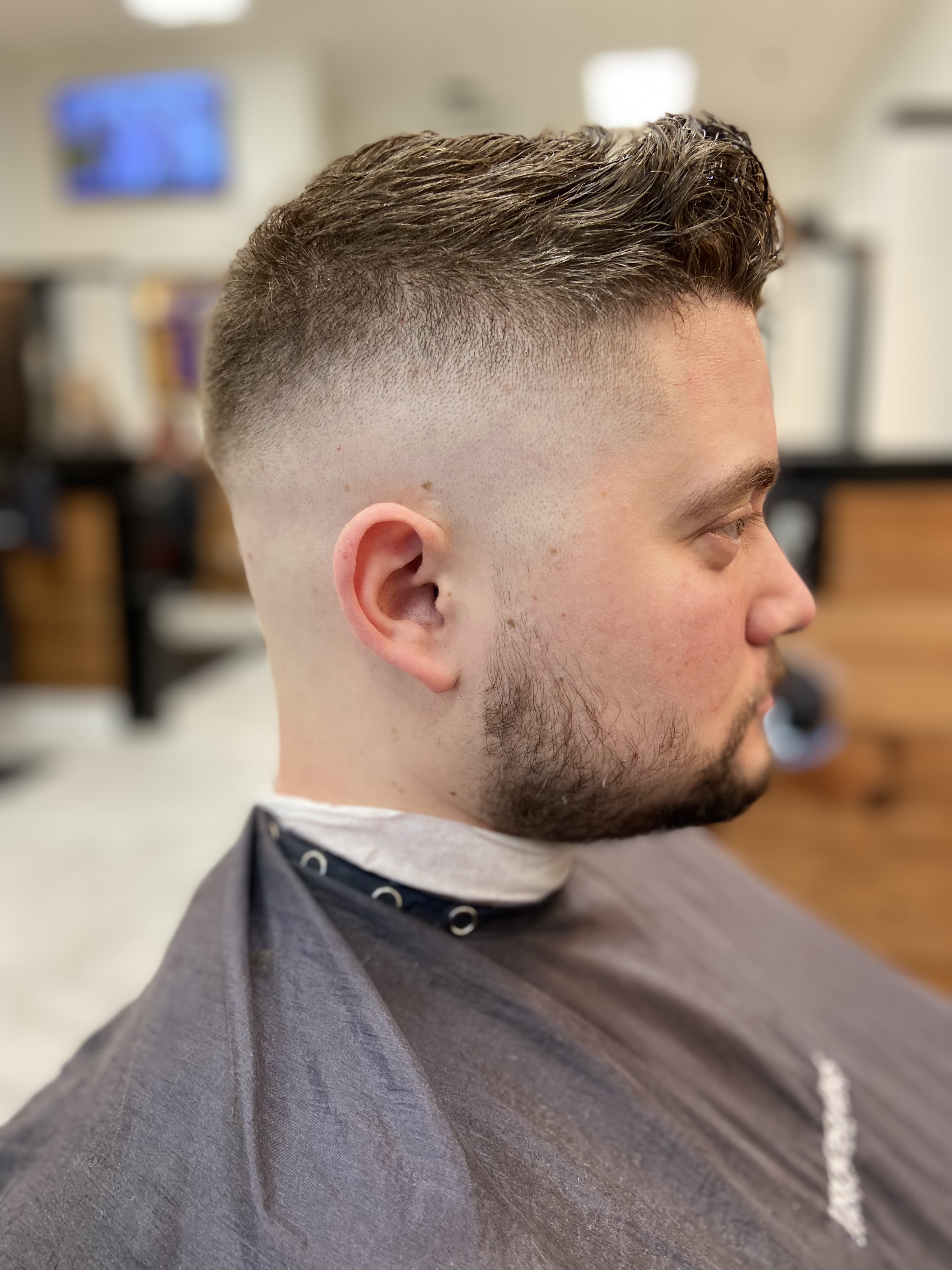 Picture of man with his hair faded down to the skin on the sides of his head. The top of his hair is spiked up towards the front of his head.